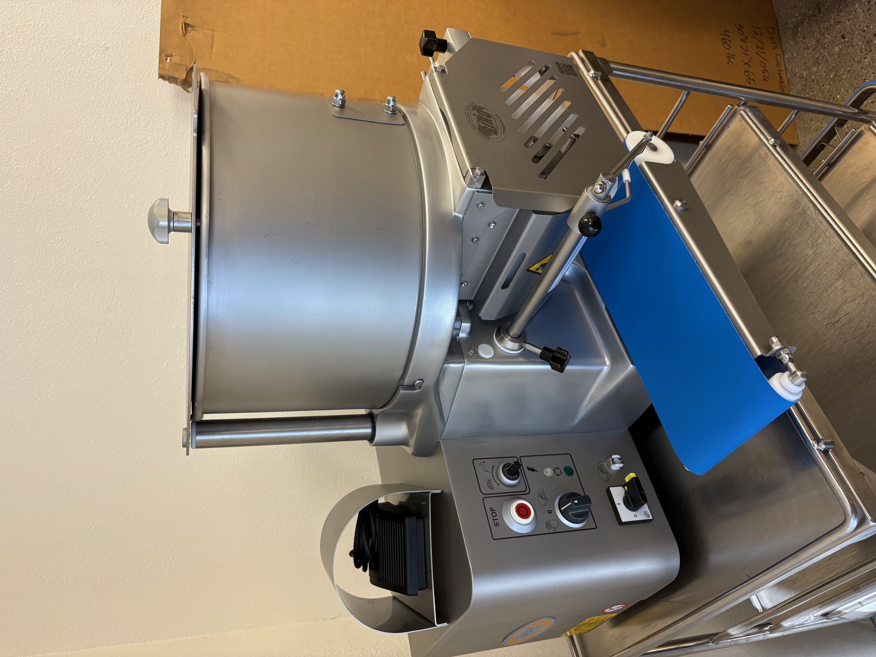 Front-left view of Biro F2000PLUSB automatic patty former showing stainless steel hopper, control panel, and blue conveyor belt on a stainless cart