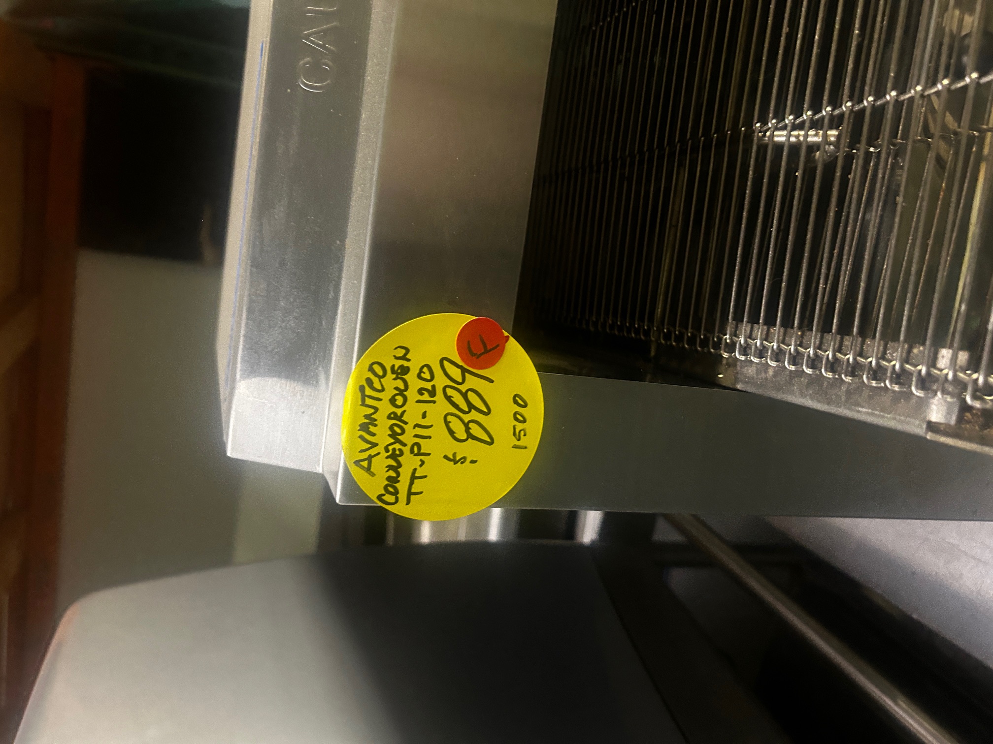 Close-up of yellow price sticker on Avantco TT-P11-120 conveyor oven showing model number, asking price of $889, and original price of $1,500