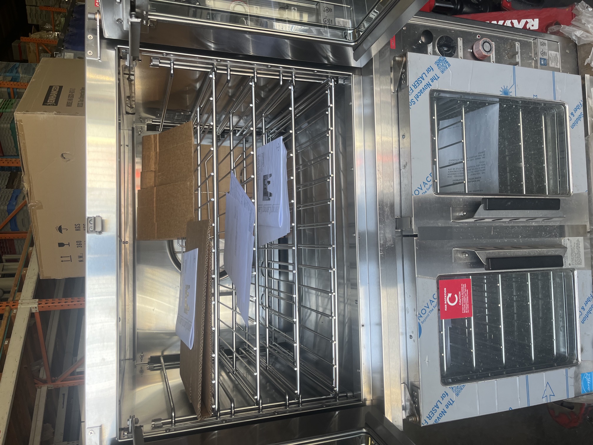 Upper deck of Lang ECOF-AT-440M convection oven with doors open showing wire racks, manuals, and accessories inside cavity