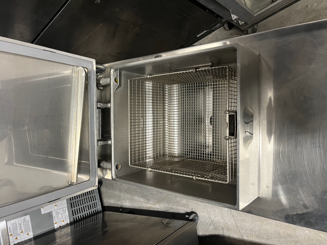 Open lid view of Henny Penny PFG-600 pressure fryer showing clean stainless steel fry pot with wire basket inside