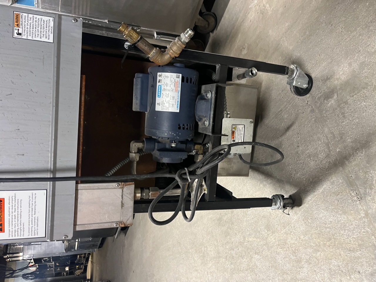 Rear view of Henny Penny PFG-600 showing Leeson electric oil filtration pump motor mounted on lower caster rack