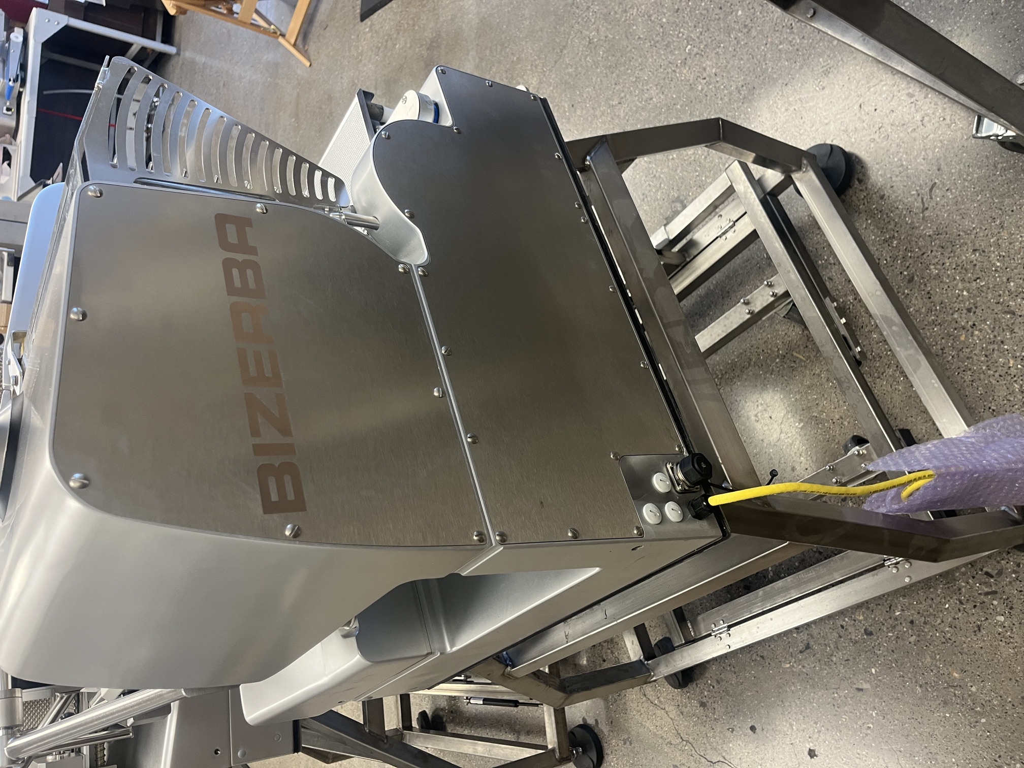 Rear view of Bizerba VSI F automatic slicer showing Bizerba branding and stainless steel housing on rolling stand