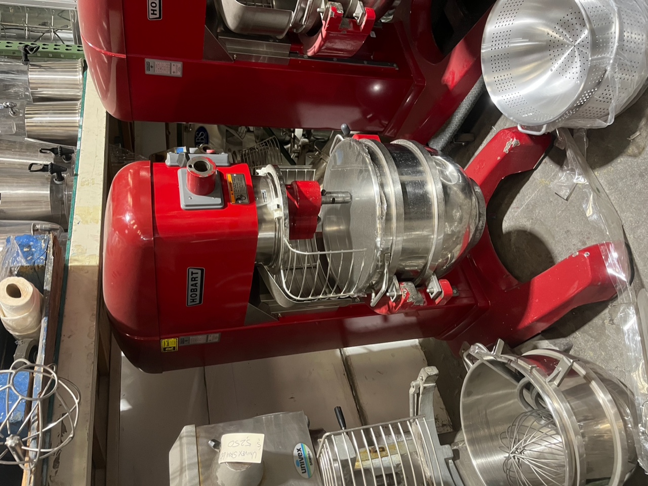 Hobart HL662 60-quart red commercial planetary mixer with stainless steel bowl and wire whip attached, front view on warehouse floor