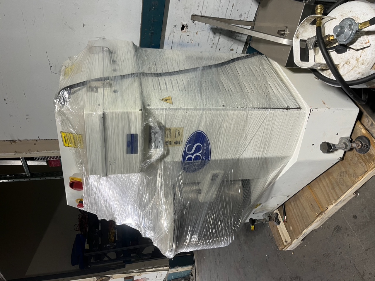 Rear view of Sinmag SM-200T spiral mixer showing ABS Baking Systems branding, emergency stop button, and adjustable leveling feet on pallet