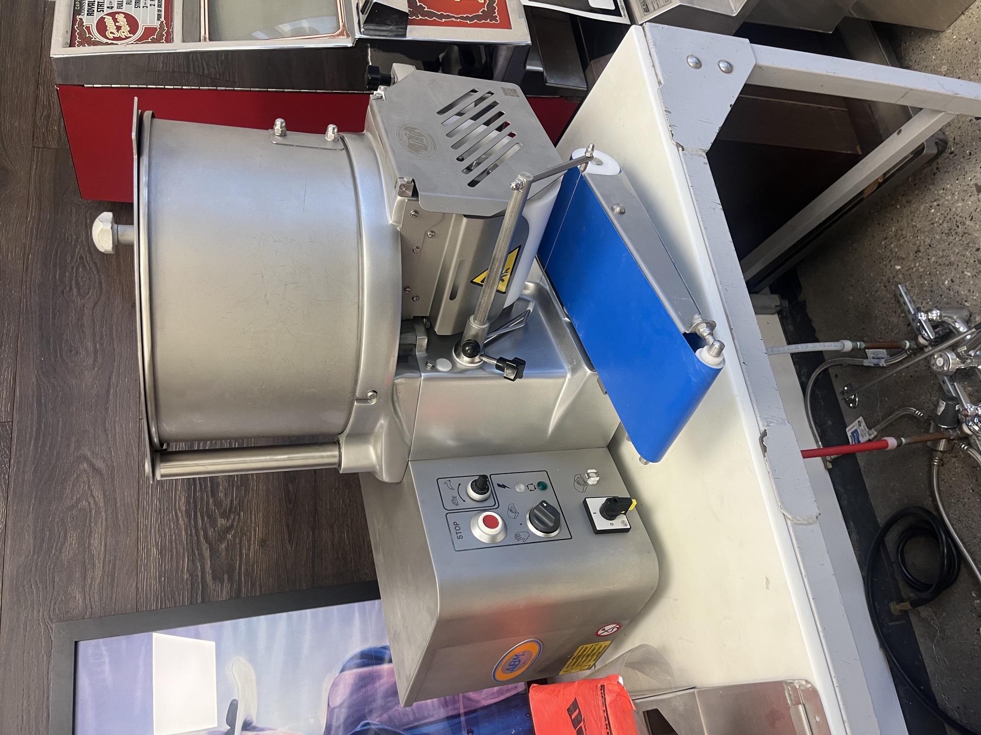 Front view of Biro F2000PLUSB automatic patty former showing control panel, hopper, and blue conveyor belt on a worktable