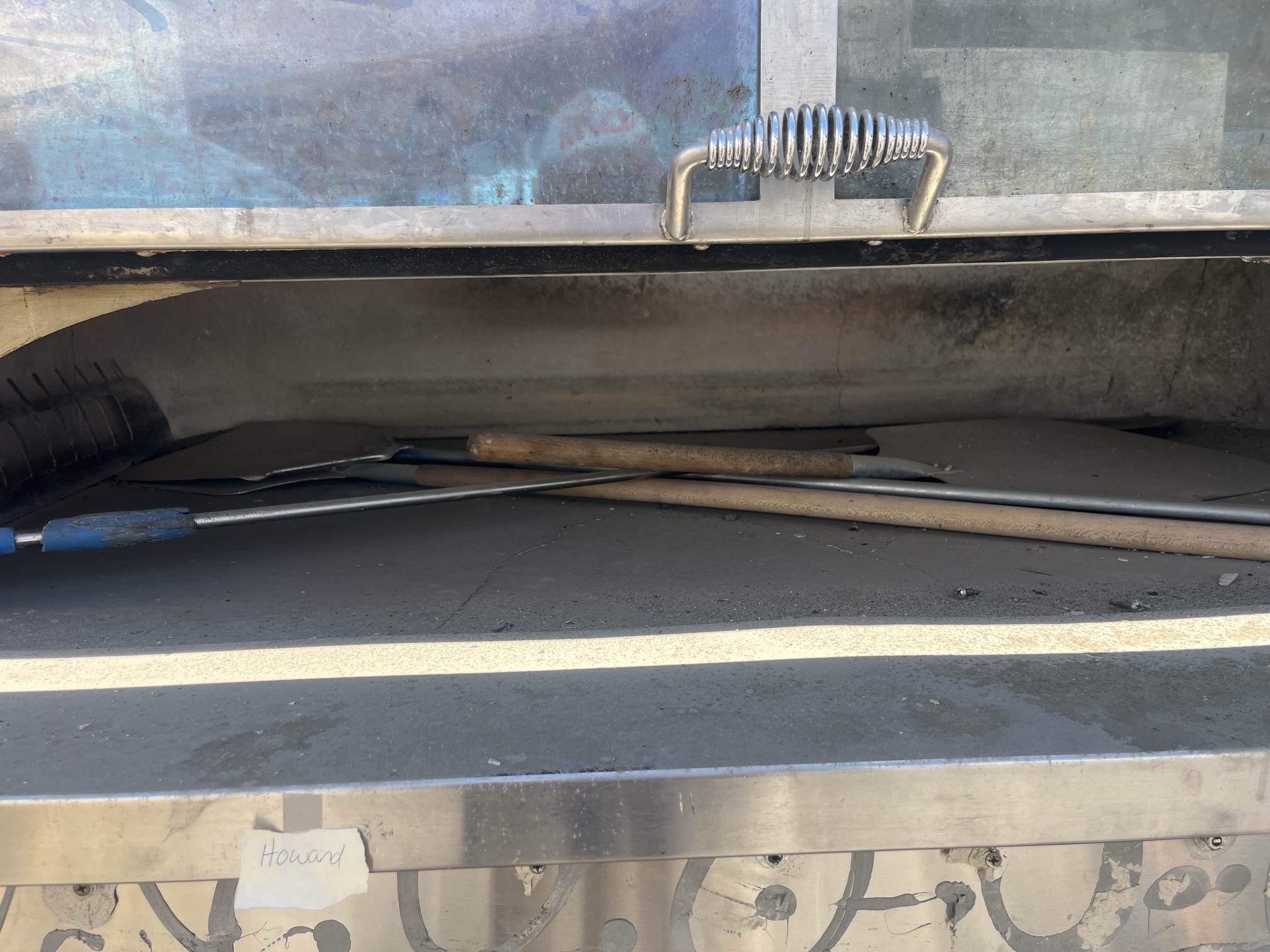 Close-up of the open stone hearth cooking deck inside the Wood Stone FD-9690 oven with pizza peels and tools resting on the stone surface