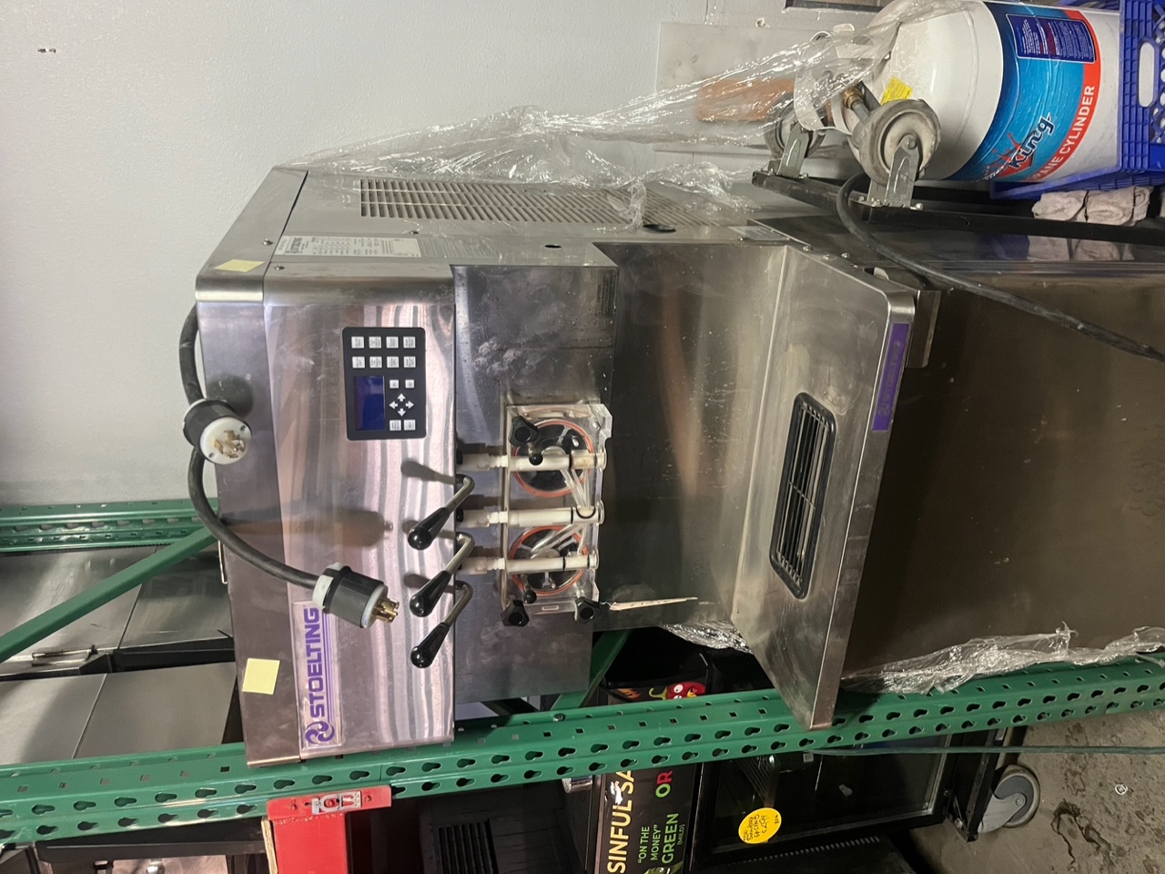 Stoelting U431-38I2 twin-twist soft serve ice cream machine on stainless steel stand with casters, showing three dispensing handles and digital control panel