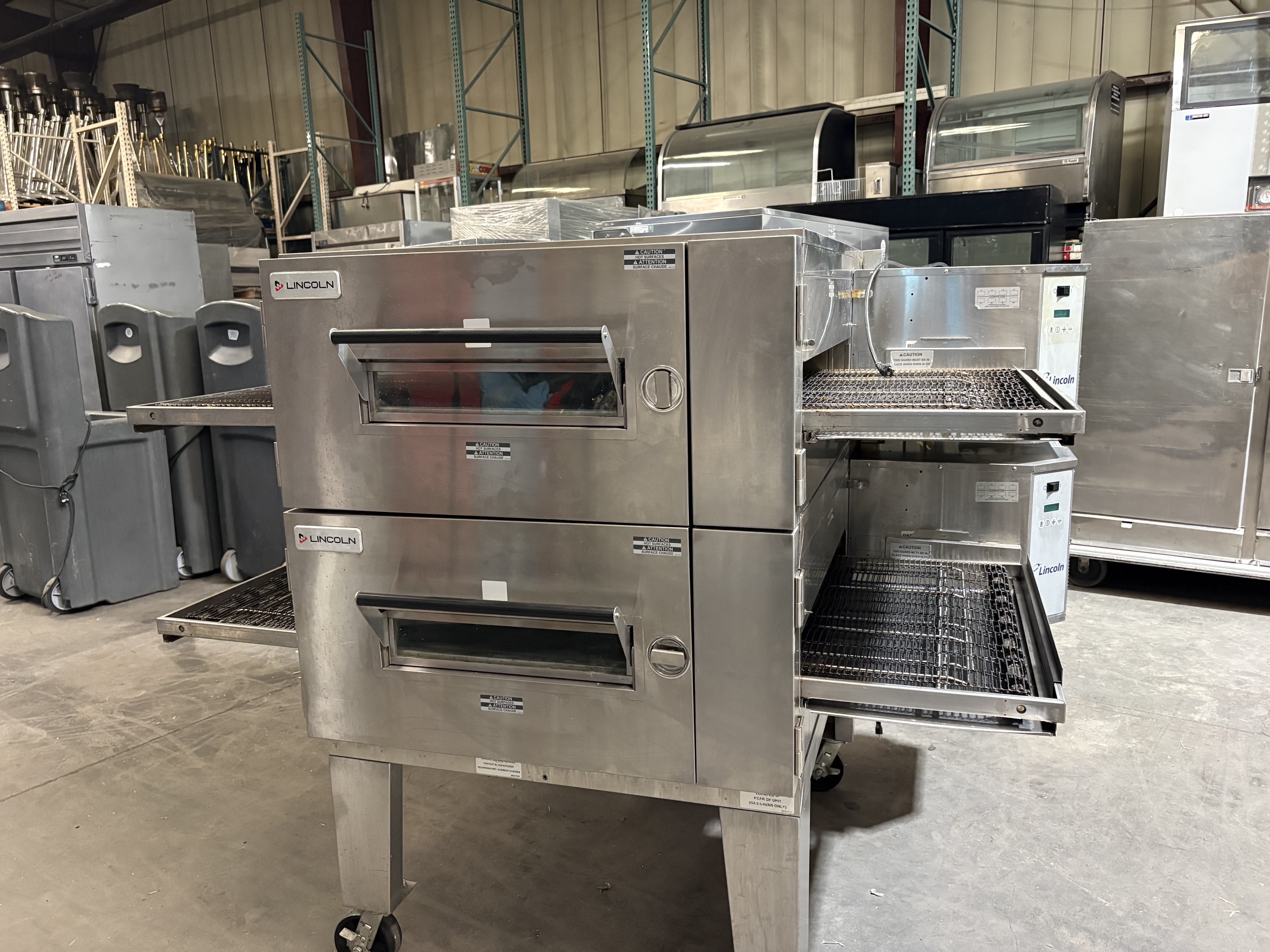 Front view of Lincoln Impinger 1600 double-stacked gas conveyor oven showing both decks with viewing windows and conveyor belts extending from the front