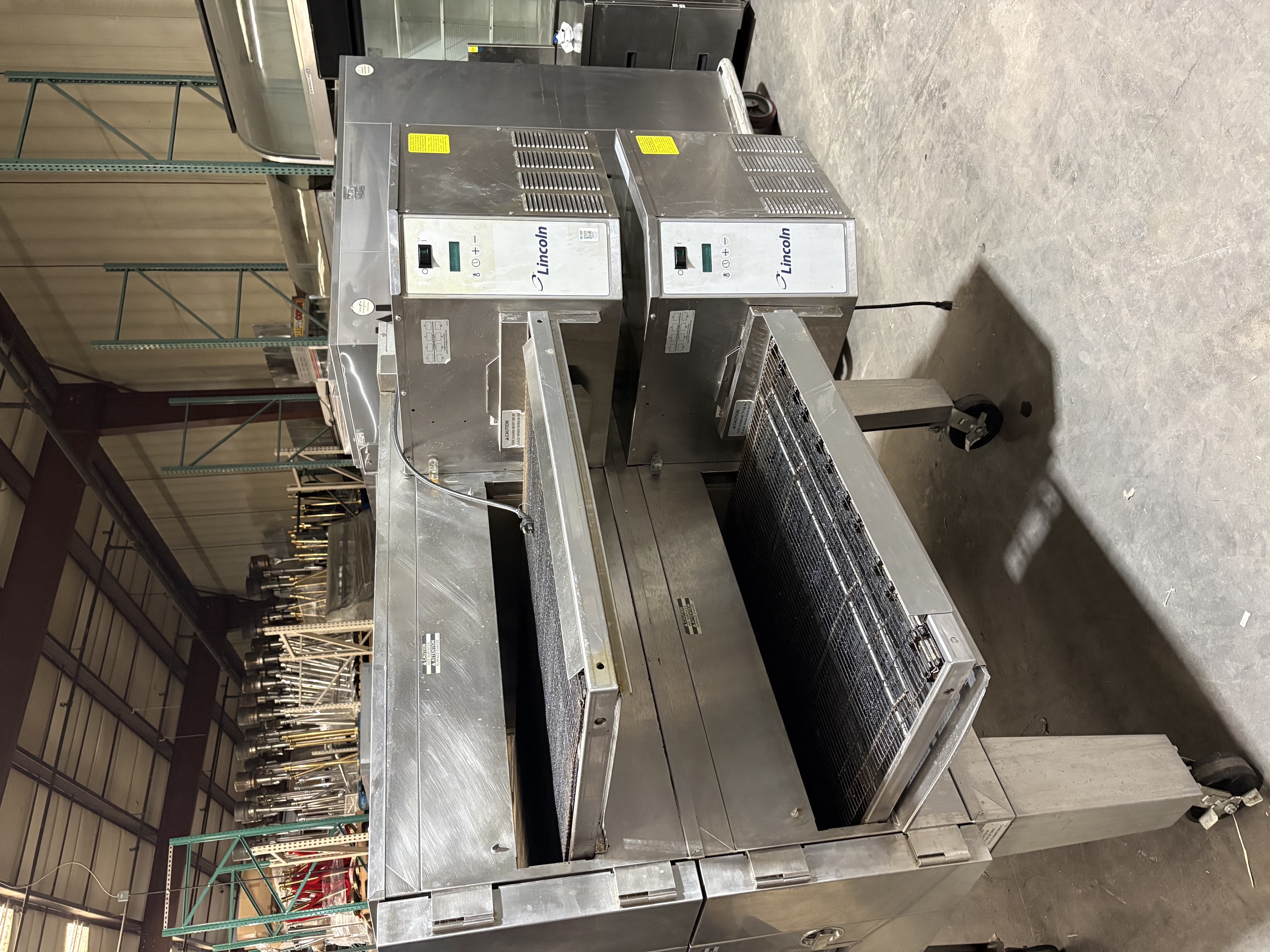 Rear angle view of Lincoln Impinger 1600 double stack oven showing digital Lincoln control panels on each deck and stainless steel stand with casters