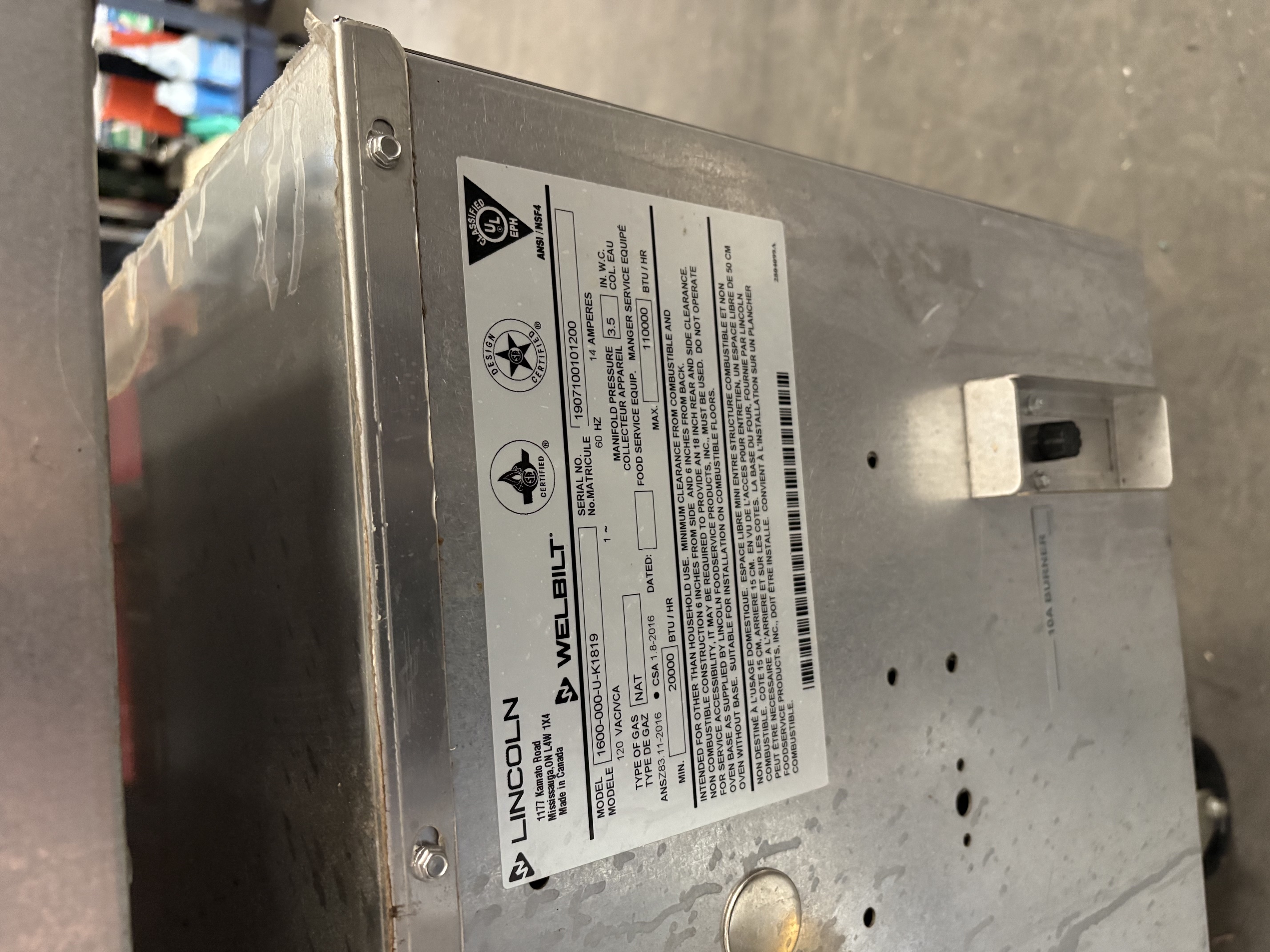 Detail of Lincoln Welbilt model data plate showing model 1600-000-U-K1819, serial number, natural gas type, 120V 14A electrical specs, and 110,000 BTU/hr max rating